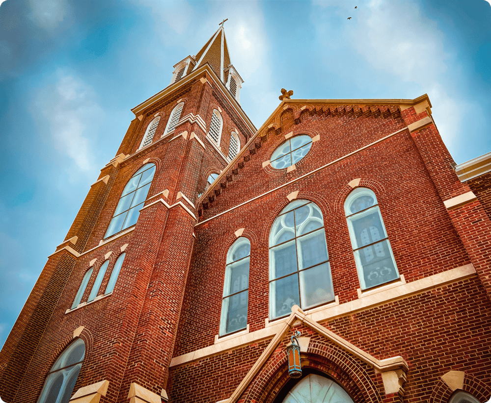 Red brick church with arched windows, sky.